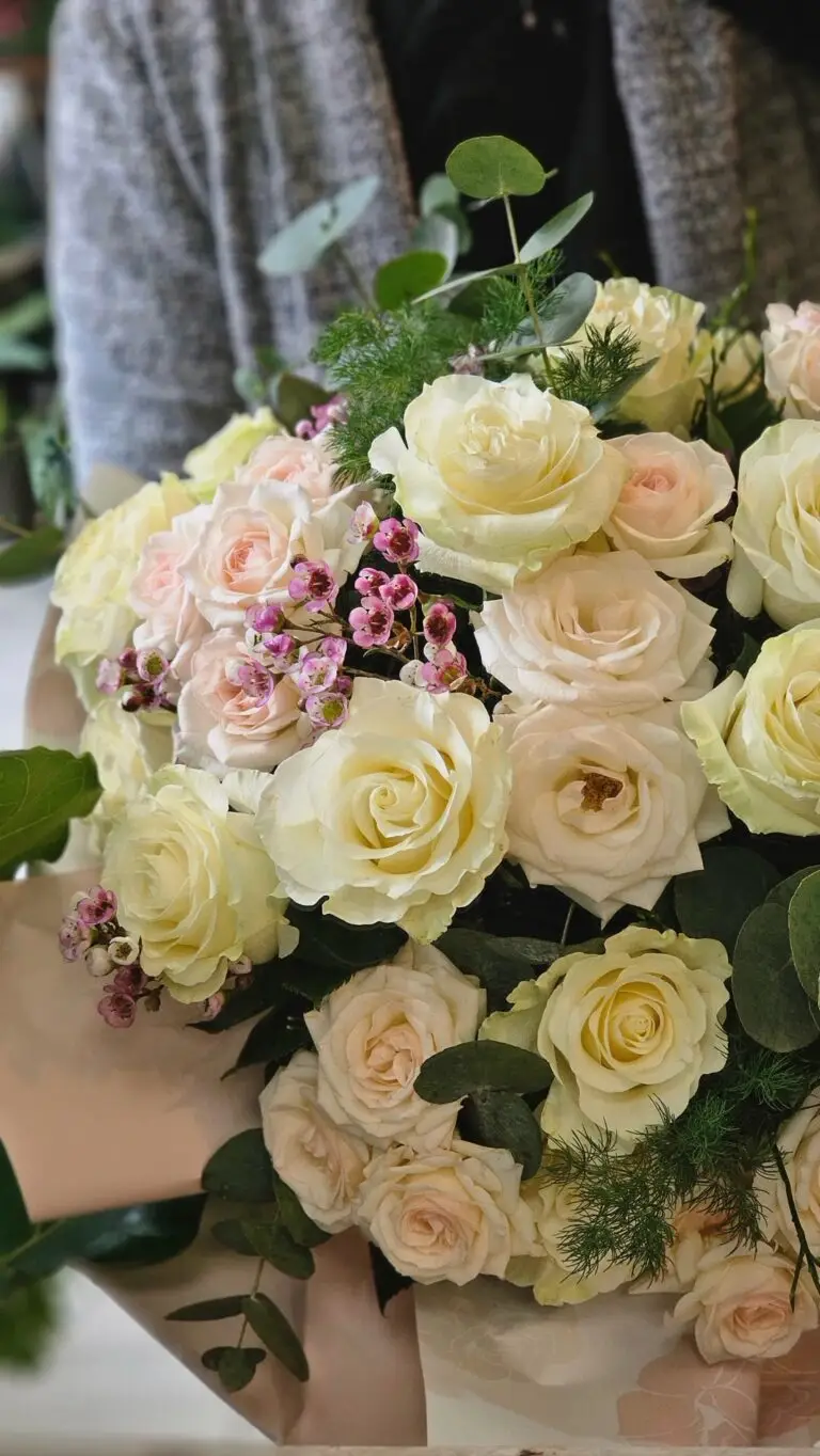 Bouquet di rose bianche e color crema con fiorellini rosa ed eucalipto, tenuto fra le braccia