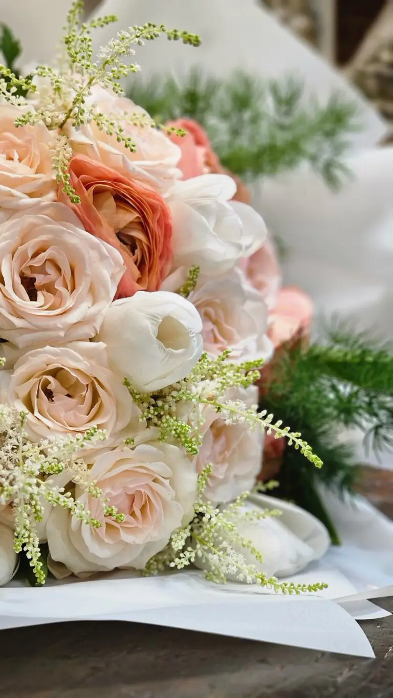Bouquet di rose cipria e pesca con tulipani bianchi e astilbe, appoggiato sulla carta da confezione