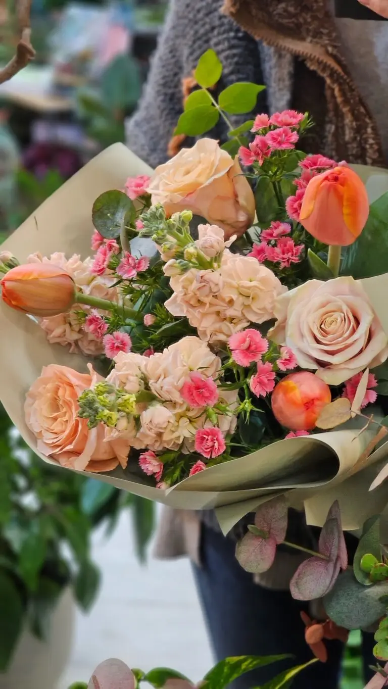 Bouquet con rose cipria, tulipani arancio, garofanini fucsia ed eucalipto, tenuto in mano