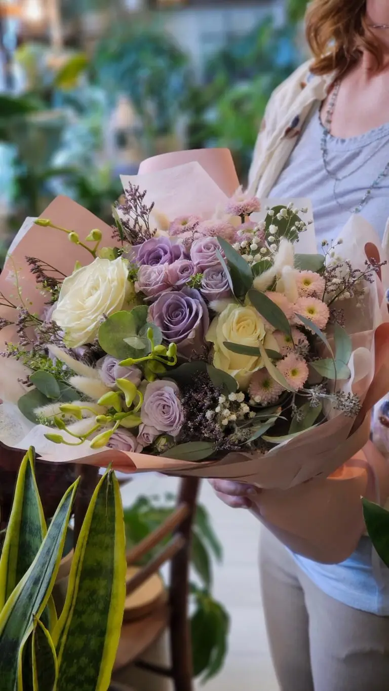 Bouquet di rose lilla e lisianthus bianchi con statice, confezionato nella carta rosa