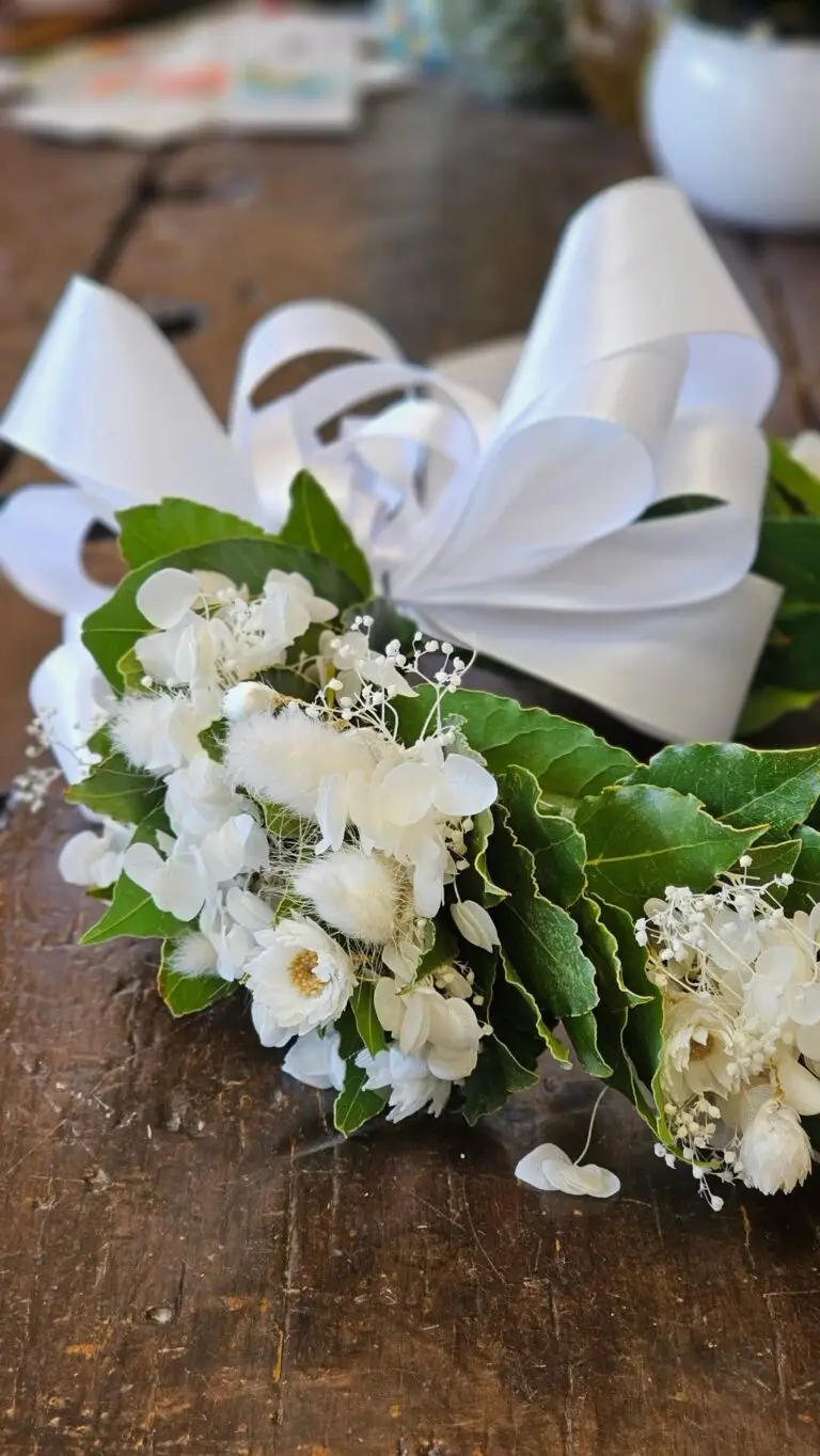 Corona di laurea in alloro con fiori bianchi e un grande fiocco di raso bianco