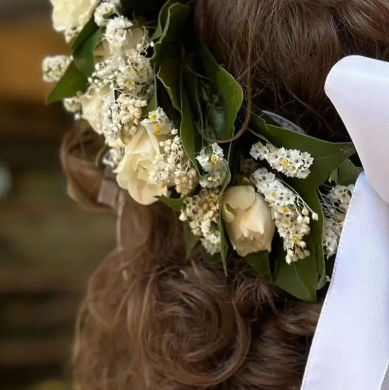 Corona di laurea con foglie di alloro e fiori chiari, realizzata a mano