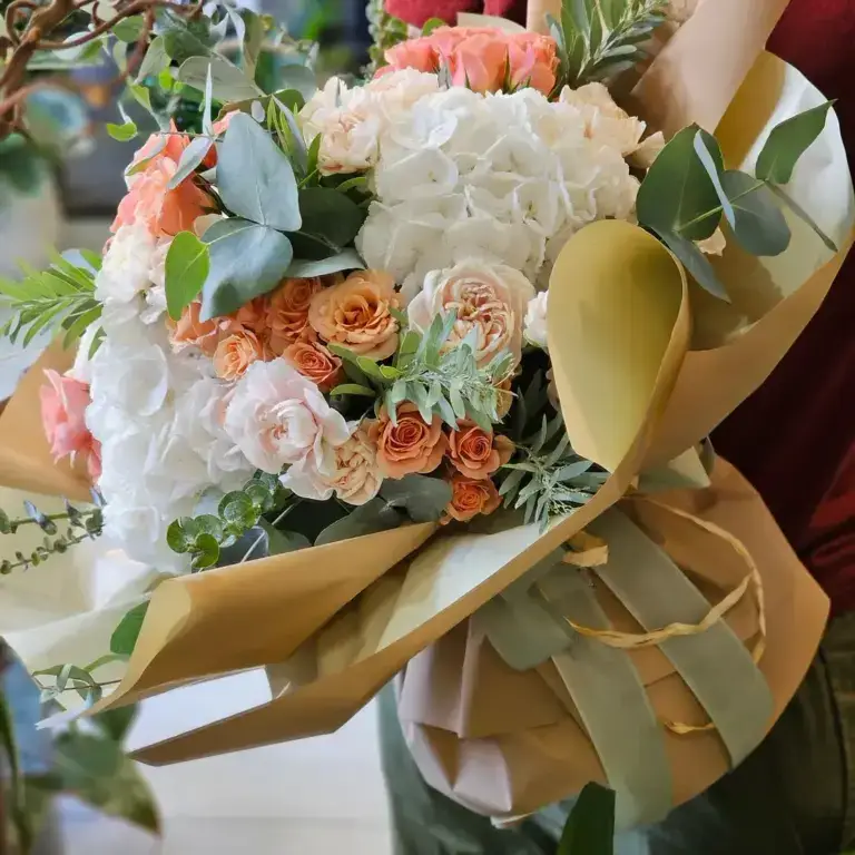 Bouquet di fiori bianchi e arancio confezionato con un nastro dorato