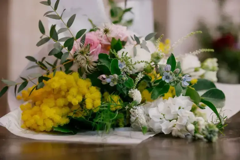Bouquet di mimosa e fiori bianchi su un banco di legno